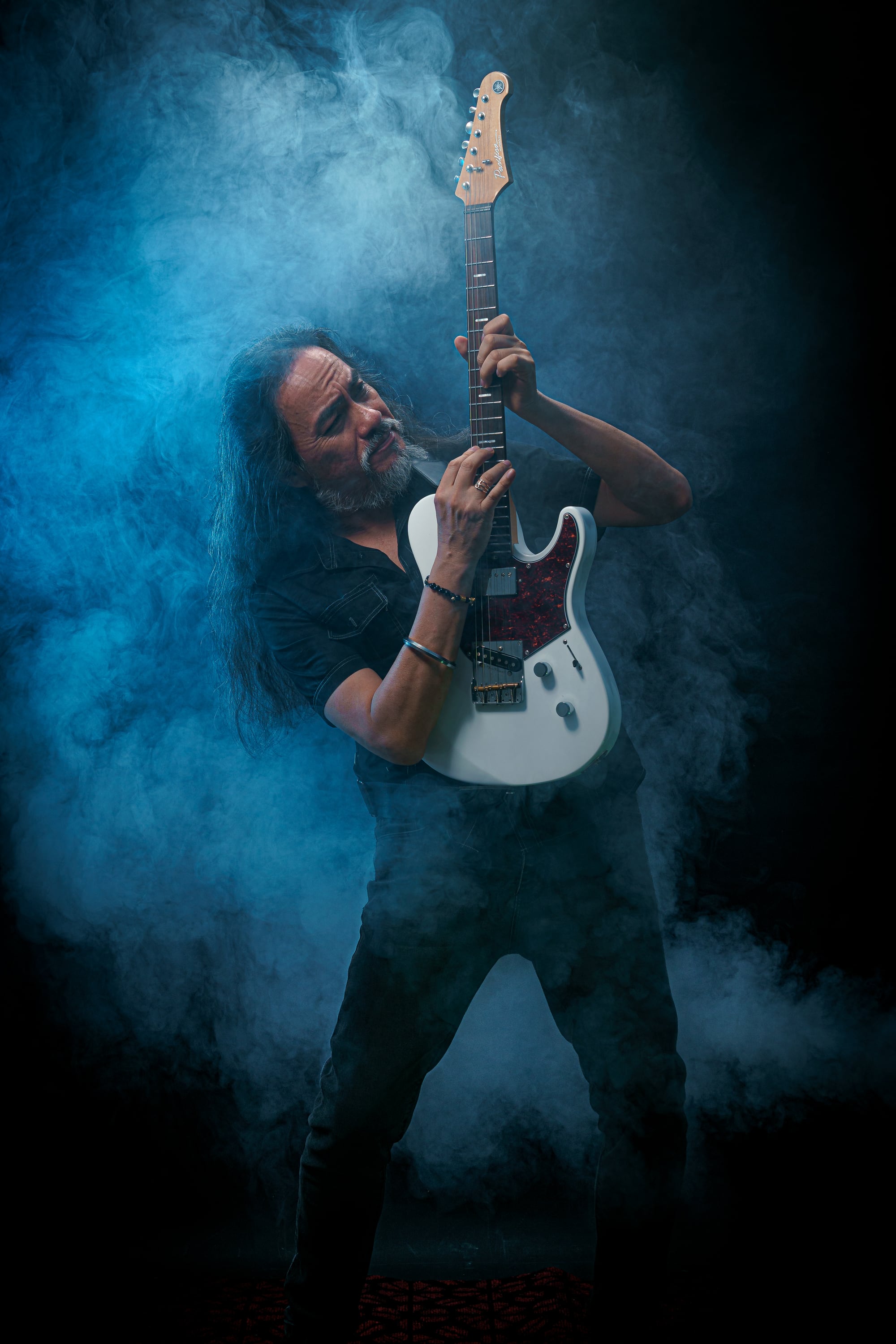 Kike Yompian interpretando guitarra eléctrica entre humo azul