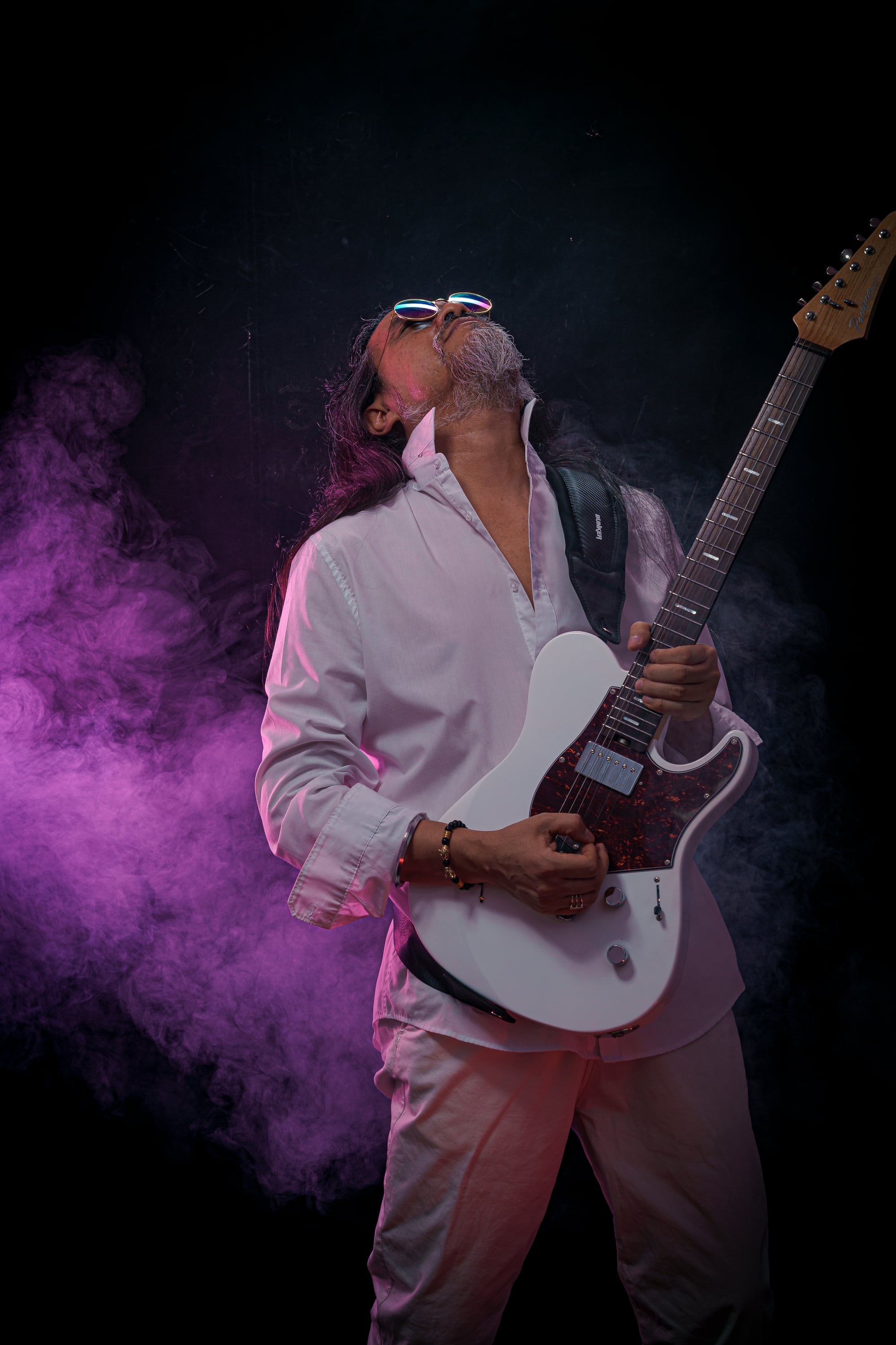 Retrato artístico de Kike Yompian con traje blanco y guitarra eléctrica